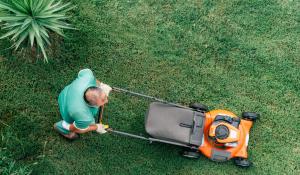 Image: man pushing an orange lawnmower. Article: 5 Steps To A More Eco-Friendly Lawn